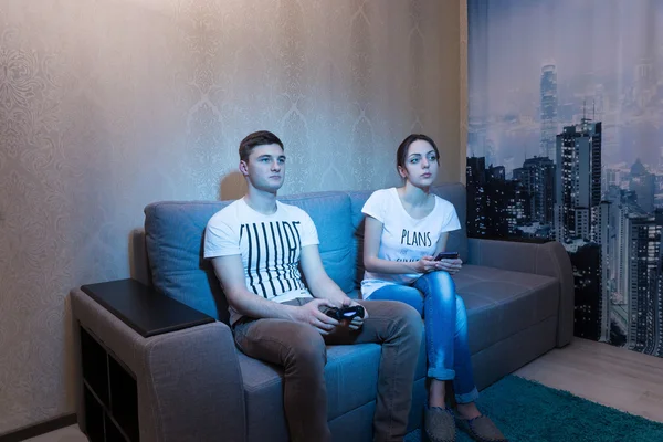 Addicted young man playing a video game sitting with his girlfri — Stock Photo, Image