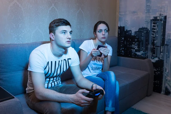 Fascinerad ung man spelar ett spel hemma med hans girlf — Stockfoto