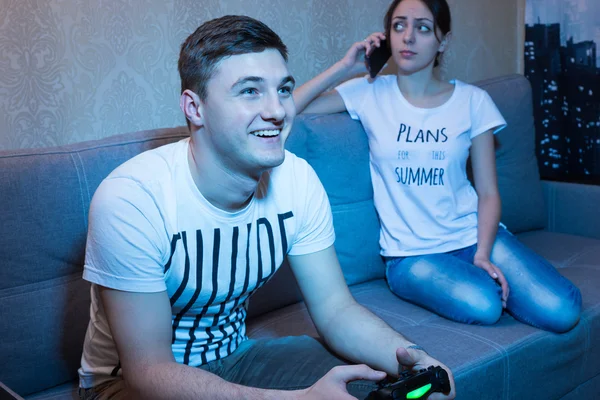 Gelukkig man afspelen van een video game terwijl zijn vriendin praten over — Stockfoto