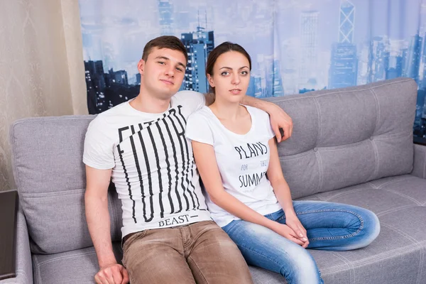 Young and romantic couple sitting on a couch together — Stock Photo, Image