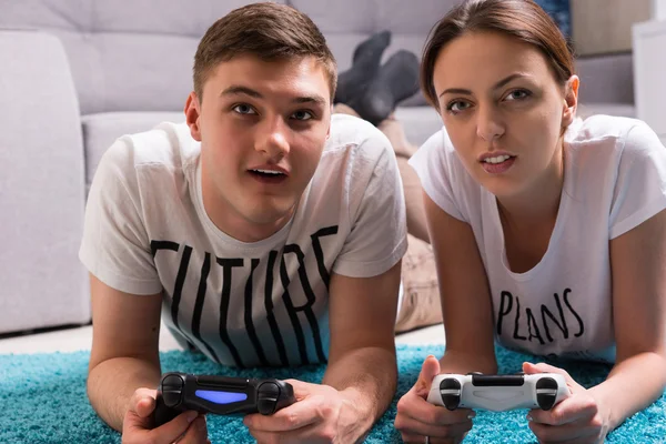 Jonge aantrekkelijke paar liggend op een tapijt spelen van videospellen — Stockfoto