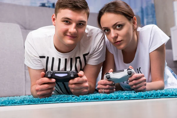 Trendy paar liggend op een tapijt spelen van videospellen — Stockfoto