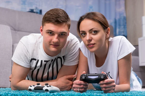 Gelukkige paar liggend op een tapijt en spelen van videospellen — Stockfoto