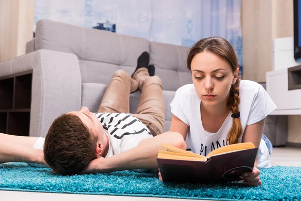 Молодая девушка читает книгу рядом со своим парнем — стоковое фото