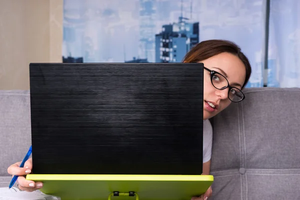 Giovane donna che indossa occhiali sbirciare dietro il computer portatile — Foto Stock
