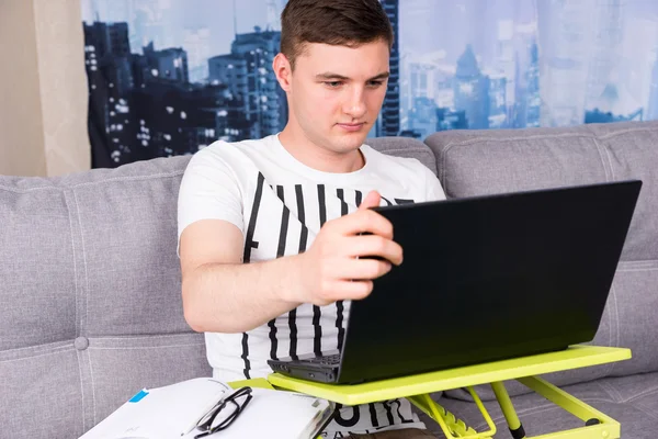 Bir dizüstü bilgisayarda çalışan ciddi yakışıklı delikanlı — Stok fotoğraf
