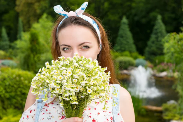 Romantische schöne junge Frau, die draußen Blumen riecht — Stockfoto