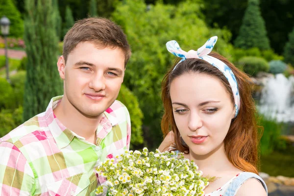 Young couple with bouquet flowers having a date outside — Stok fotoğraf