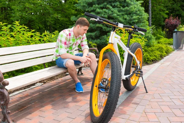 Uomo solitario in pantaloncini seduto sulla panchina vicino alla bici — Foto Stock