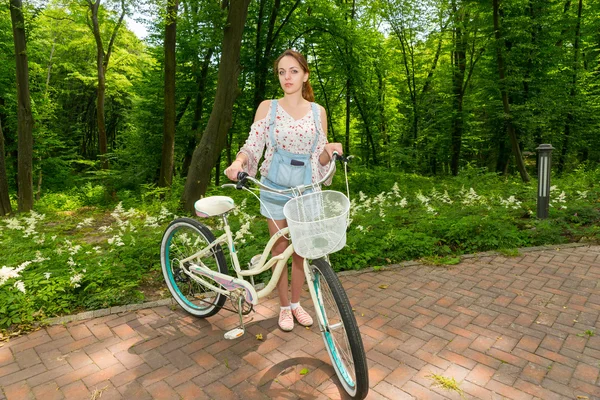Женщина с велосипедом, стоящим на кирпичах в парке — стоковое фото