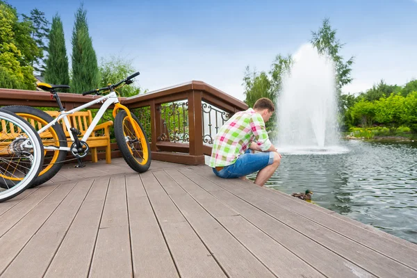 Guy zit op het houten dek na het fietsen — Stockfoto