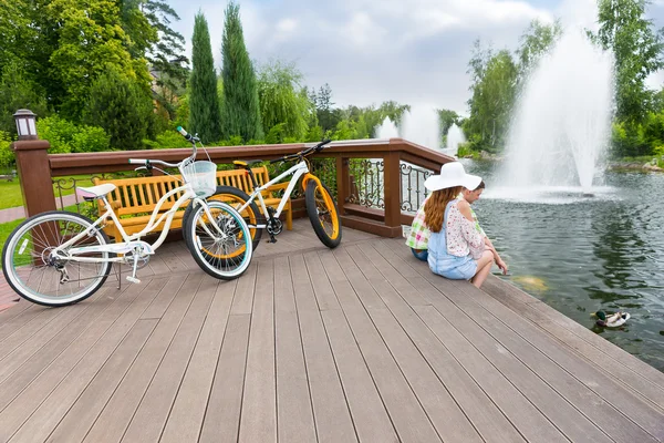 Пара сидящих на деревянной палубе после езды на велосипеде и кормления уток — стоковое фото