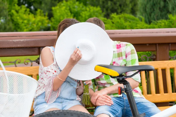 Fashionable man and woman kissing hiding behind the hat — Stock Photo, Image