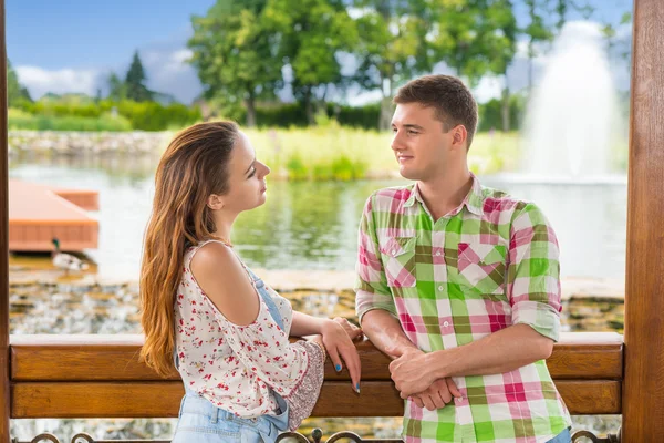 Young romantic couple leaning on railing of the wooden gazebo  a — Stock Photo, Image