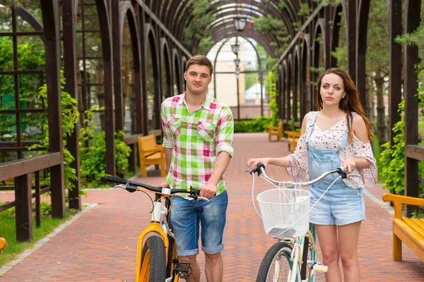 Jovem par atraente com bicicletas em arco — Fotografia de Stock