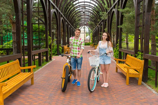 Молодой человек и женщина с велосипедами в арке — стоковое фото