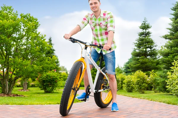 Потрясающий красивый мужчина, сидящий на велосипеде в парке — стоковое фото