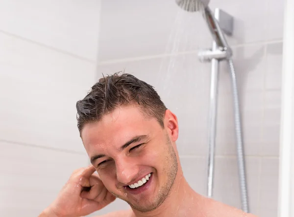 若い男が浴室でシャワーを浴びながら彼の耳をクリーニング — ストック写真