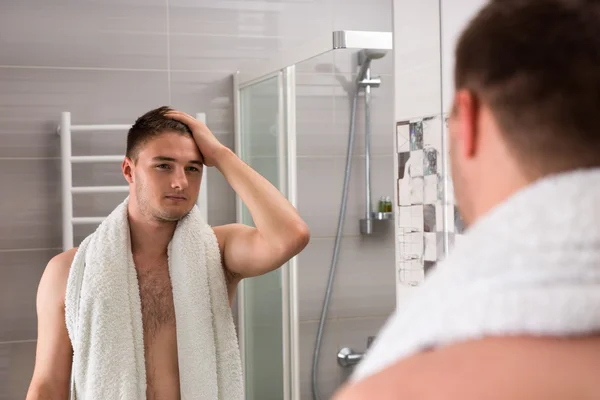 Bonito masculino segurando toalha em seus ombros enquanto olha em th — Fotografia de Stock