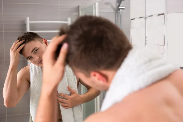 Νεαρός άνδρας κρατώντας πετσέτα στους ώμους κατά τη διόρθωση των μαλλιών — Φωτογραφία Αρχείου