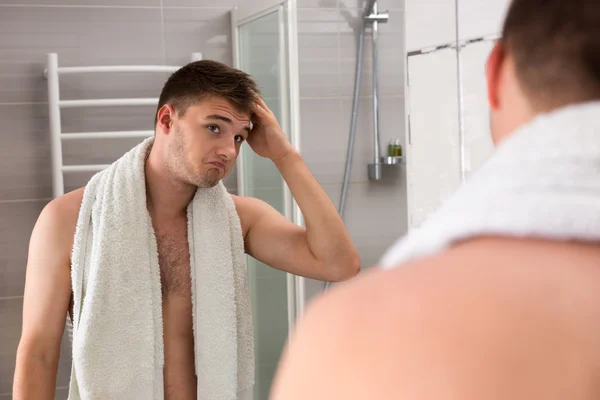 Masculino segurando toalha em seus ombros enquanto corrige o cabelo — Fotografia de Stock