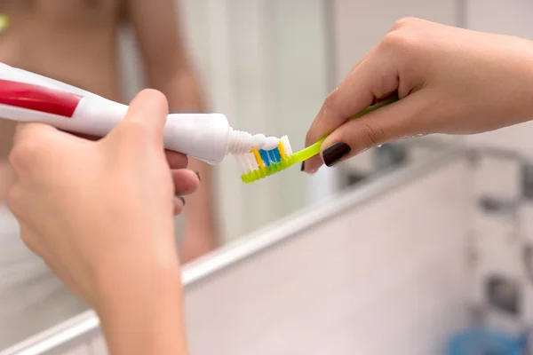 Manos sosteniendo un cepillo de dientes y colocando pasta de dientes en él — Foto de Stock