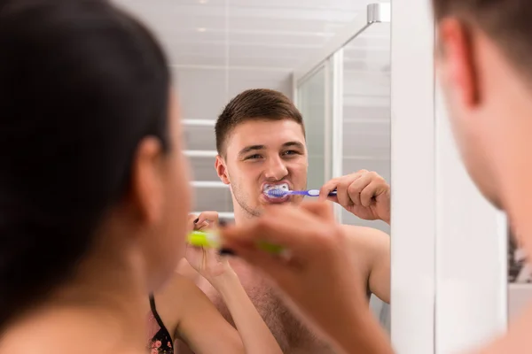 Close up jovem escovar os dentes com a namorada no morcego — Fotografia de Stock
