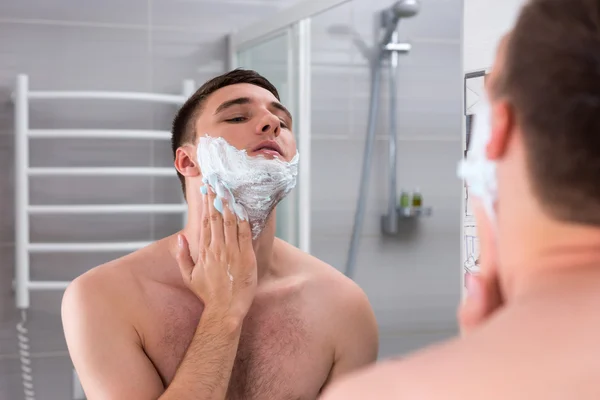 Άνθρωπος που πασαλείβουν αφρό για ξύρισμα στο πρόσωπό του στο μπάνιο — Φωτογραφία Αρχείου