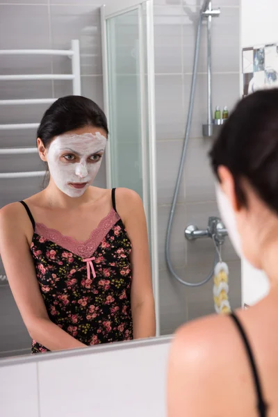 Portrait of female with cosmetic mask on face looking at herself — Stock Photo, Image