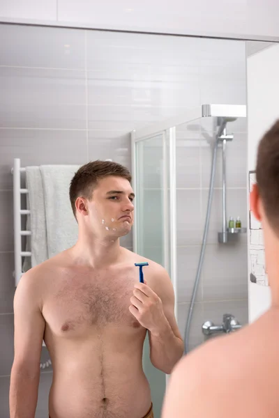 Handsome male  with cuts on his face after bad shaving  holding — Stock Photo, Image