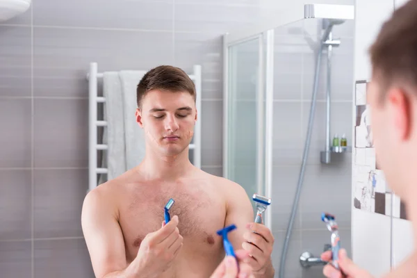 Hombre sosteniendo máquinas de afeitar y elige el mejor, mientras que de pie en el b — Foto de Stock