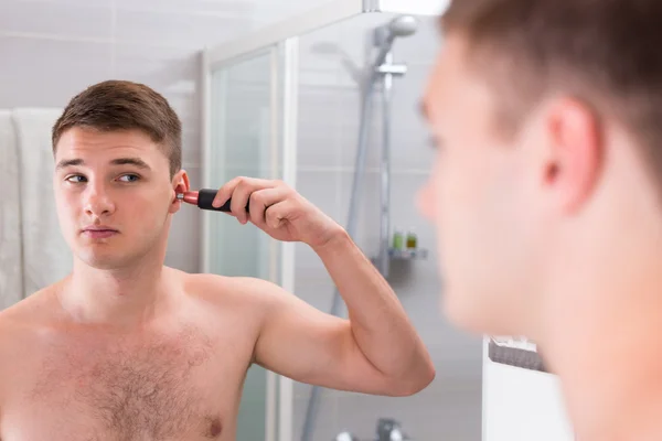 Handsome man shaving his ear with trimmer — Stock Photo, Image