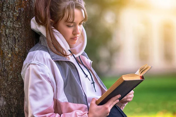 Ładna Młoda Dziewczyna Siedzi Czytając Książkę Lub Studiuje Świeżym Powietrzu — Zdjęcie stockowe