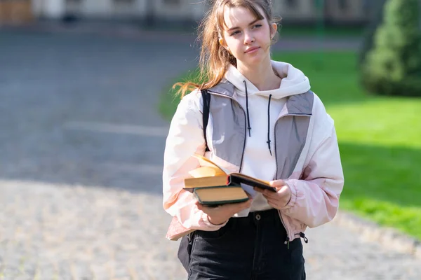 Przemyślana Młoda Kobieta Niosąca Książki Dłoniach Spacerując Brukowanym Chodnikiem Parku — Zdjęcie stockowe