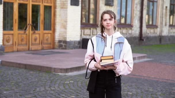 Kitaplarını ve çantasını taşıyan genç bir öğrenci. — Stok video