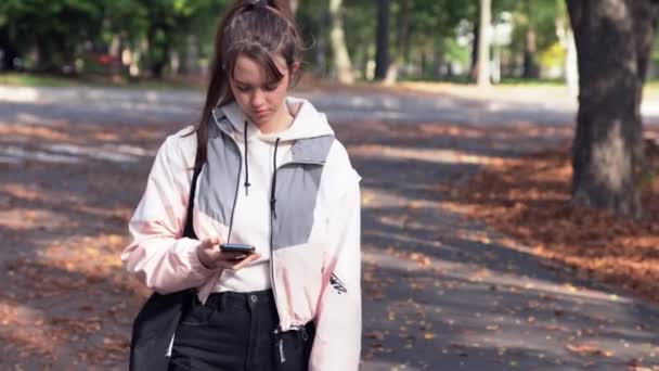 Jovem adolescente lendo uma mensagem enquanto caminha — Vídeo de Stock