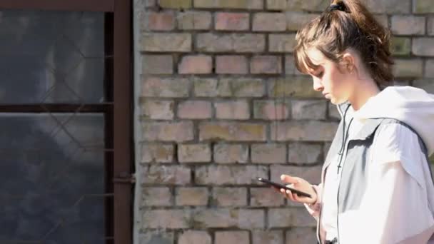 Joven adolescente caminando con su teléfono móvil — Vídeos de Stock