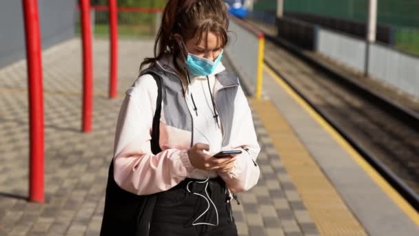 Дівчина-підліток у масці, що стоїть на платформі — стокове відео