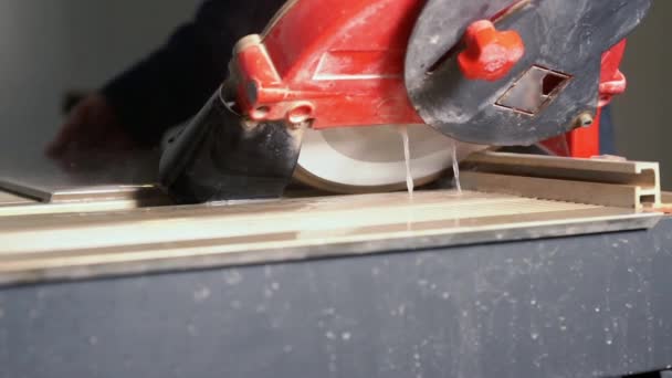 Рабочий, разрезающий плитку или панель с помощью пилы — стоковое видео