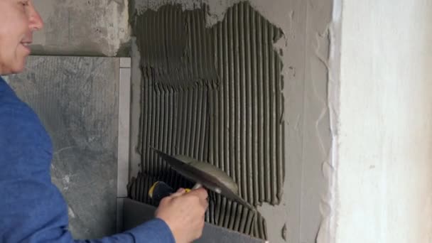 Costruttore applicando fresco adesivo piastrelle a una parete — Video Stock