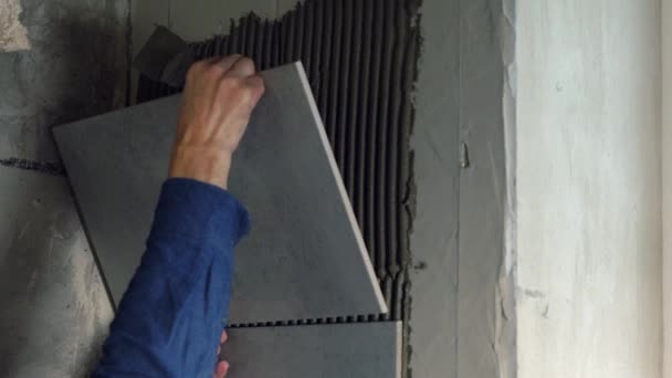 Construtor aplicando telhas grandes em uma parede — Vídeo de Stock