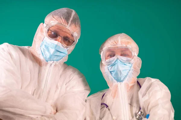Two physicians with face shields in PPE suit uniforms wearing medical protective Masks