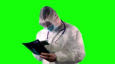 PPE giysisi, yüz kalkanı ve maskesi takan doktor, hastaların röntgenlerini inceliyor. Covid üzerinde test etmek için.