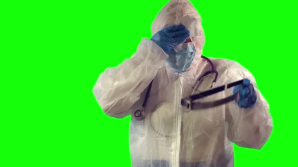 Médecin surmené enlève un écran facial et essuie la sueur avec une serviette après une dure journée pendant la période covid-19, sur fond vert. — Video