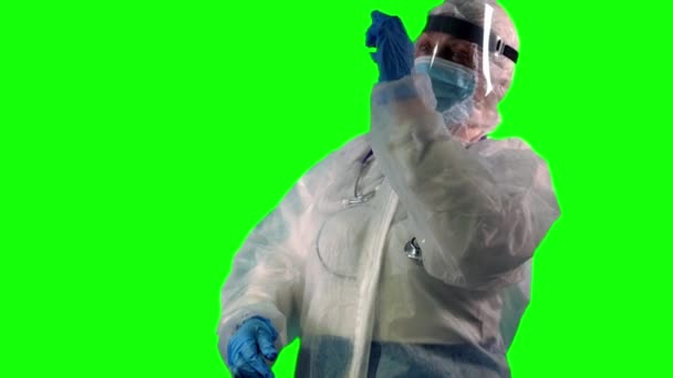 Un médecin portant une combinaison EPI tient et examine un flacon avec un vaccin pour guérir le coronavirus, sur fond vert — Video