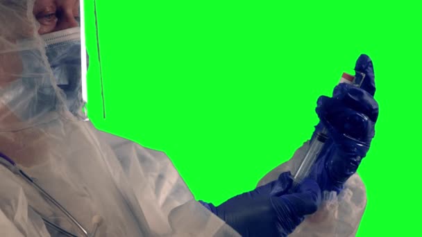 Un médecin en combinaison EPI et écran facial tient une seringue et un vaccin COVID-19 dans des gants en nitrile bleu, se préparant à faire une injection — Video