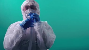 Yorgun doktor, PPE üniformasını çözüyor ve zor bir günün ardından maske ve gözlük çıkarıyor.