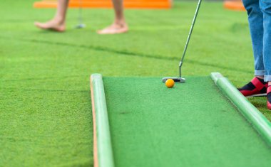Minyatür golf ya da suni açık hava sahasında topun ve kulübün düşük açılı görüntüsünde mini golf oynayan biri.
