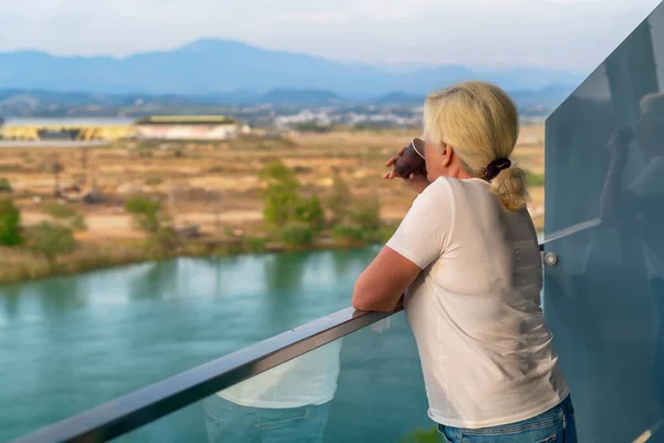 Женщина Стоящая Возвышенном Открытом Балконе Потягивая Кофе Наблюдая Рекой Озером — стоковое фото