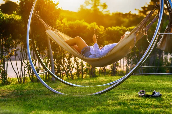 Femme Relaxant Dans Hamac Dans Jardin Coucher Soleil Utilisant Son — Photo